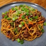 Asian beef spaghetti in a bowl with green onions