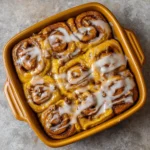 A golden, gooey cinnamon roll bake with icing drizzled on top
