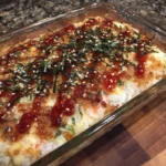 A golden, cheesy sushi bake casserole topped with nori and sesame seeds.